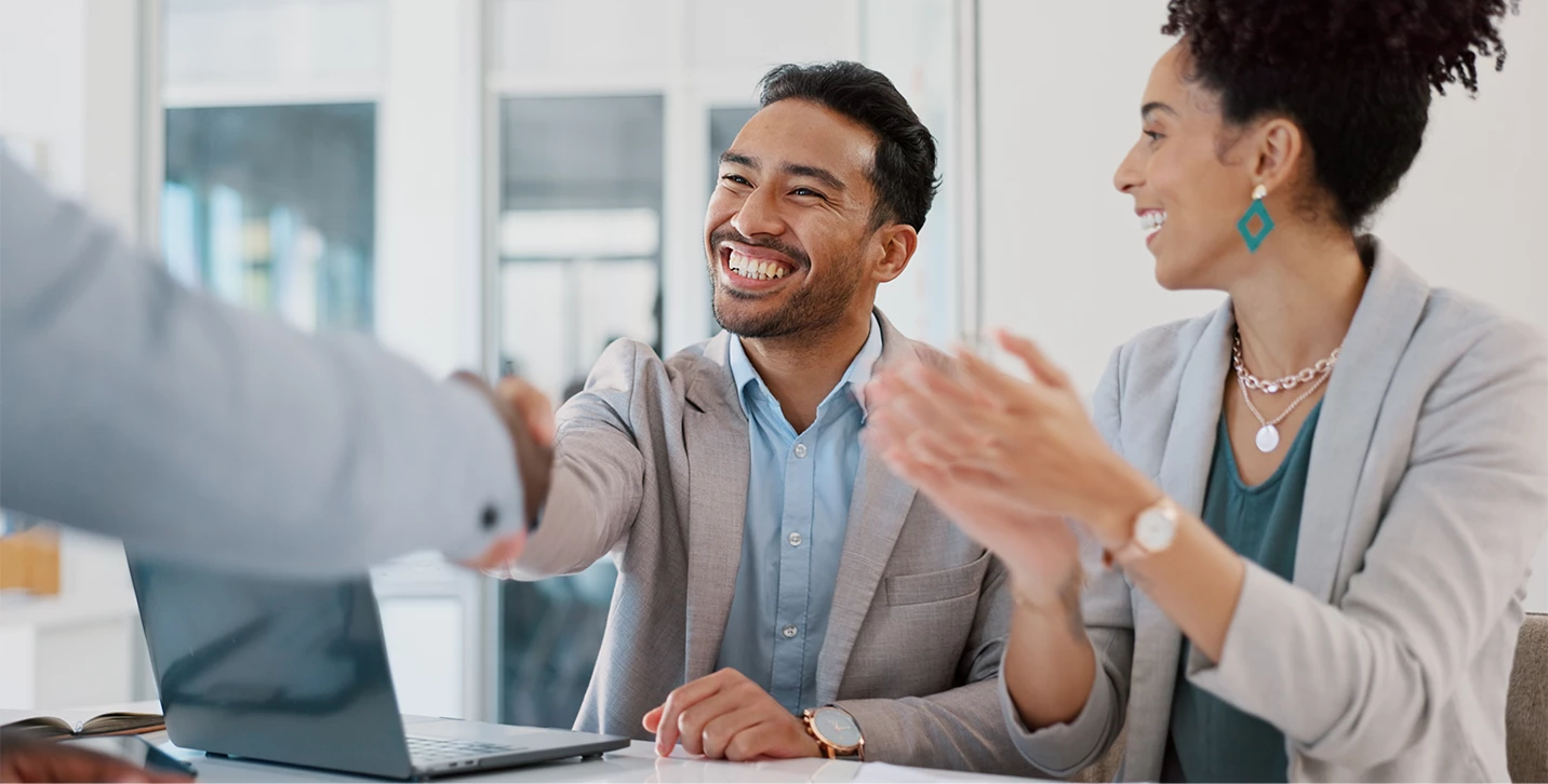  A man smiling and shaking someone’s hand.