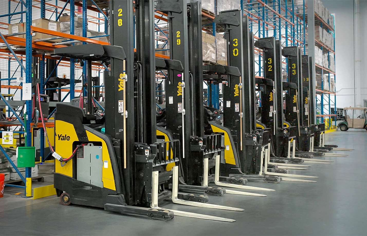 A row of Yale lithium-ion powered lift trucks recharging in a warehouse.