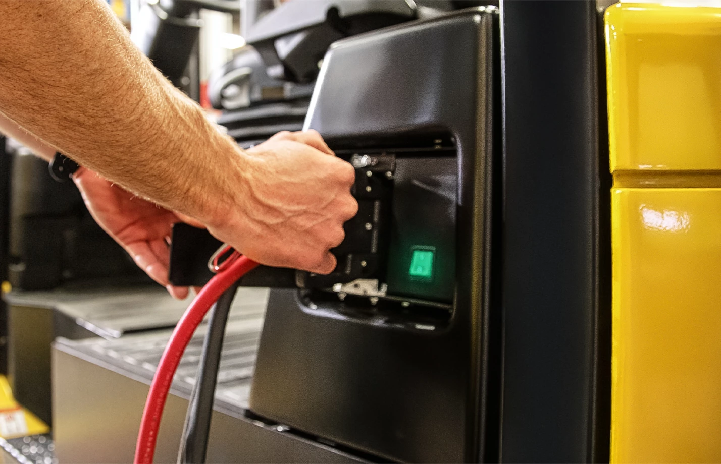 Man connecting a charging cable to a Yale forklift.