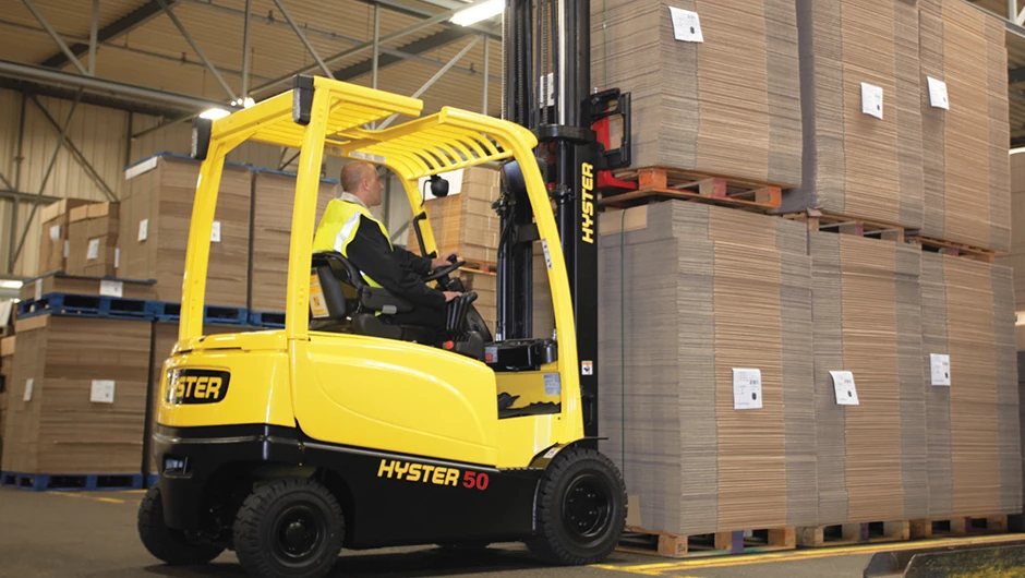 Hyster electric forklift picking up load of packaging materials.   