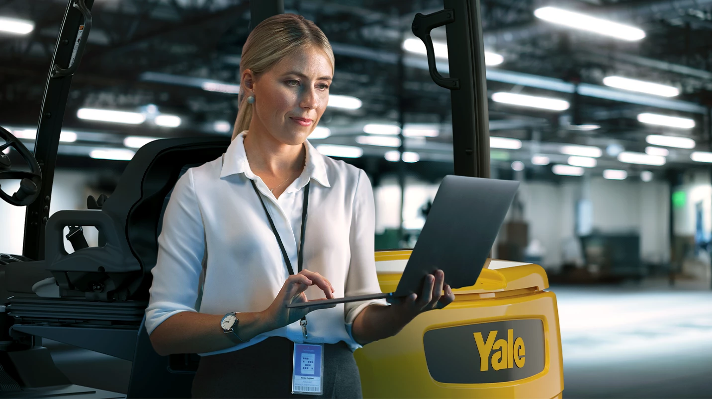 Women on laptop with Yale forklift behind her.