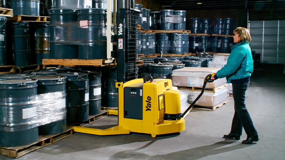 Person picking loads with Yale walkie pallet stacker in warehouse. 