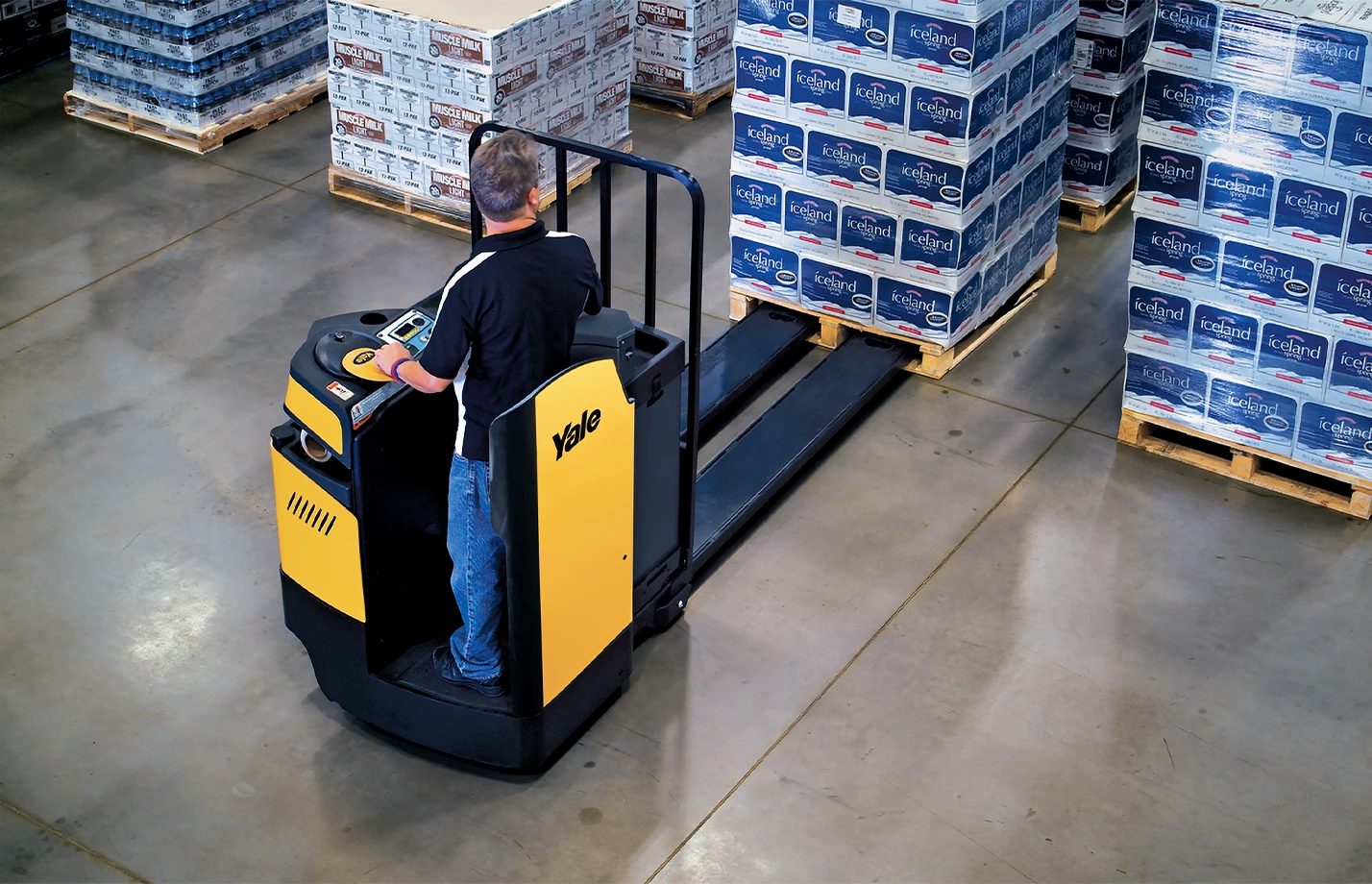 Operator using a Yale enclosed end rider lift truck to move a pallet in a beverage warehouse.