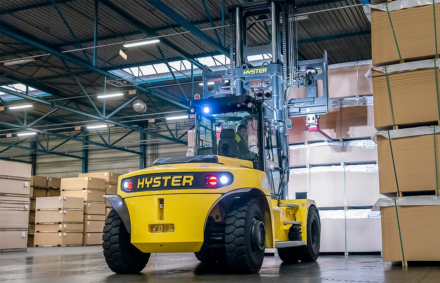 Operator driving a Hyster high-capacity forklift at a cargo port.